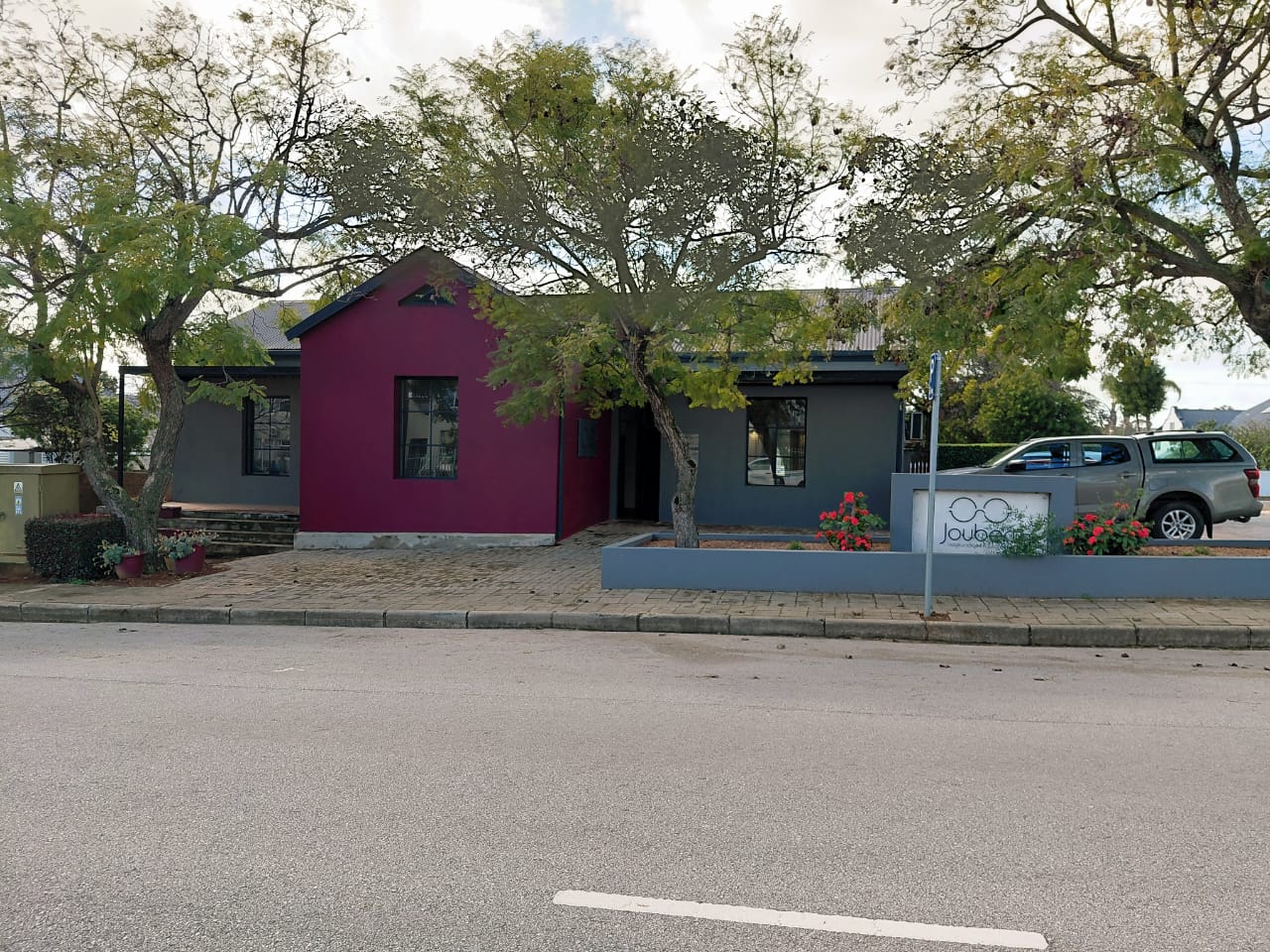 Joubert Oogkundiges street view — dark grey and deep burgundy facade with practice signage among the trees
