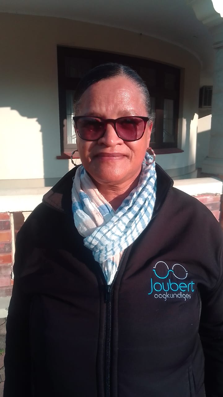 Joubert Optometrists team member in a black branded jacket outdoors